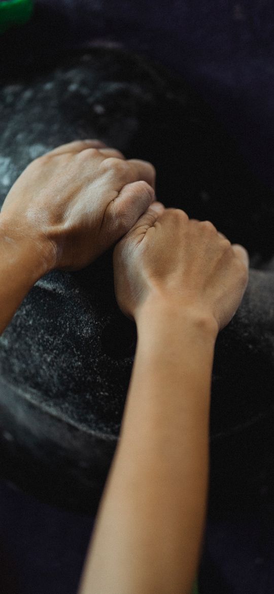 Chalked hands gripping a large dark hold